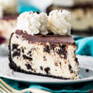 slice of oreo cheesecake topped with chocolate ganache and whipped cream