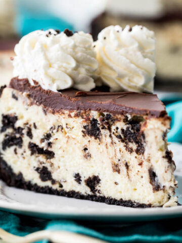 slice of oreo cheesecake topped with chocolate ganache and whipped cream