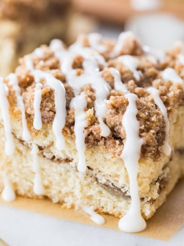 square slice of cinnamon coffee cake with a cinnamon swirl middle, crumb topping, and vanilla drizzle glaze