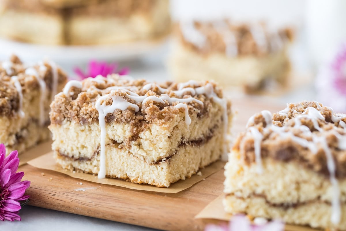 square slices of cake with a crumb topping, cinnamon swirl middle, and vanilla drizzle