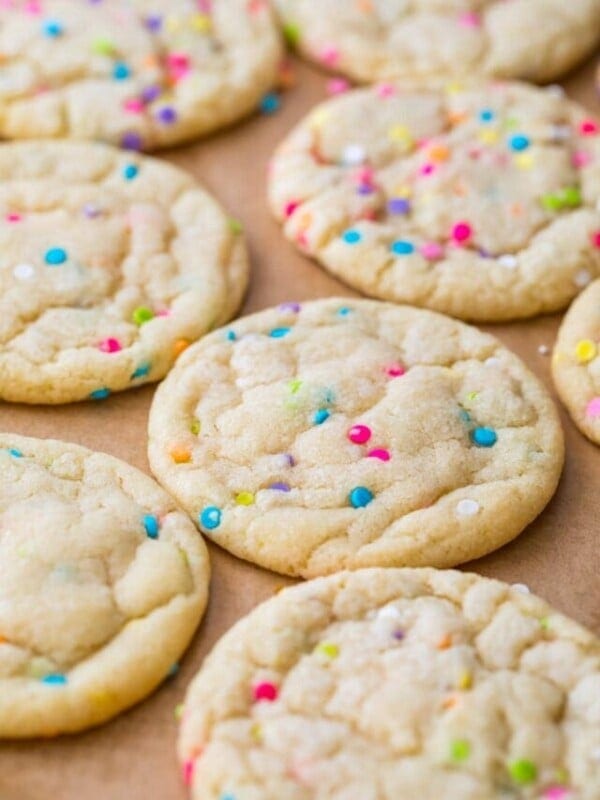 sugar cookies baked with colorful sprinkles resting on a parchment lined baking sheet