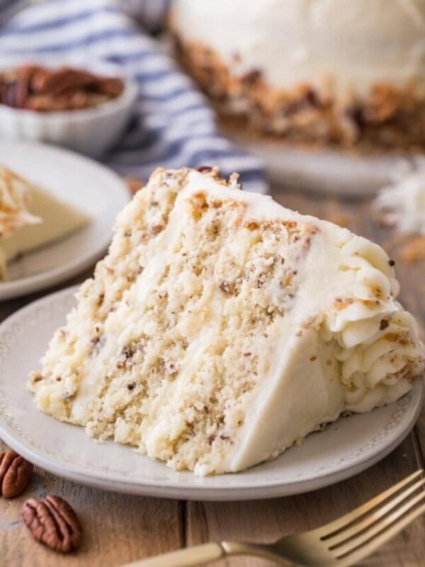 slice of cake consisting of three layers studded with coconut and chopped pecans frosted with cream cheese frosting