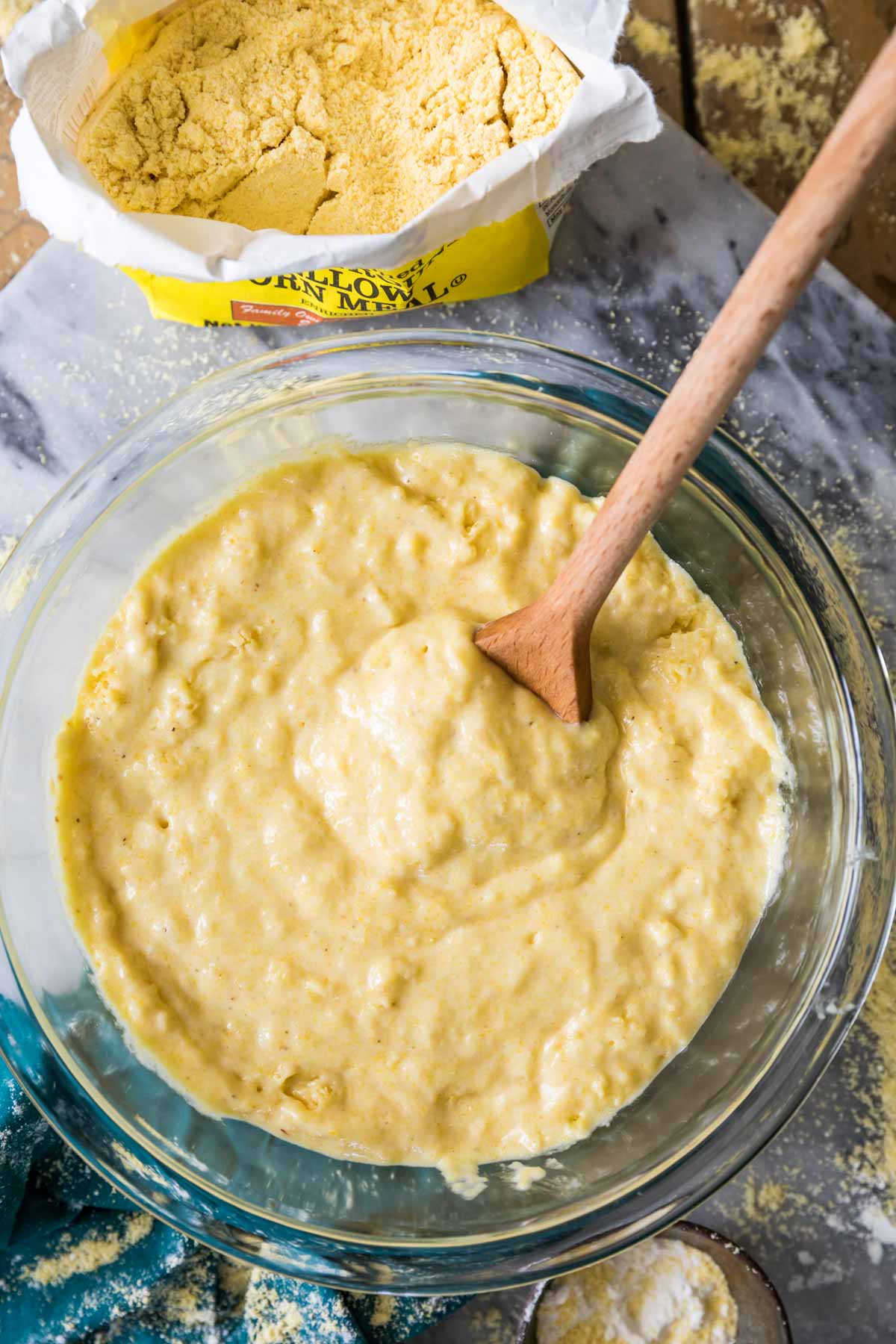 overhead view of cornbread batter being stirred with a wooden spoon