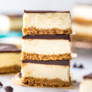 three ganache covered cheesecake bars stacked on top of each other