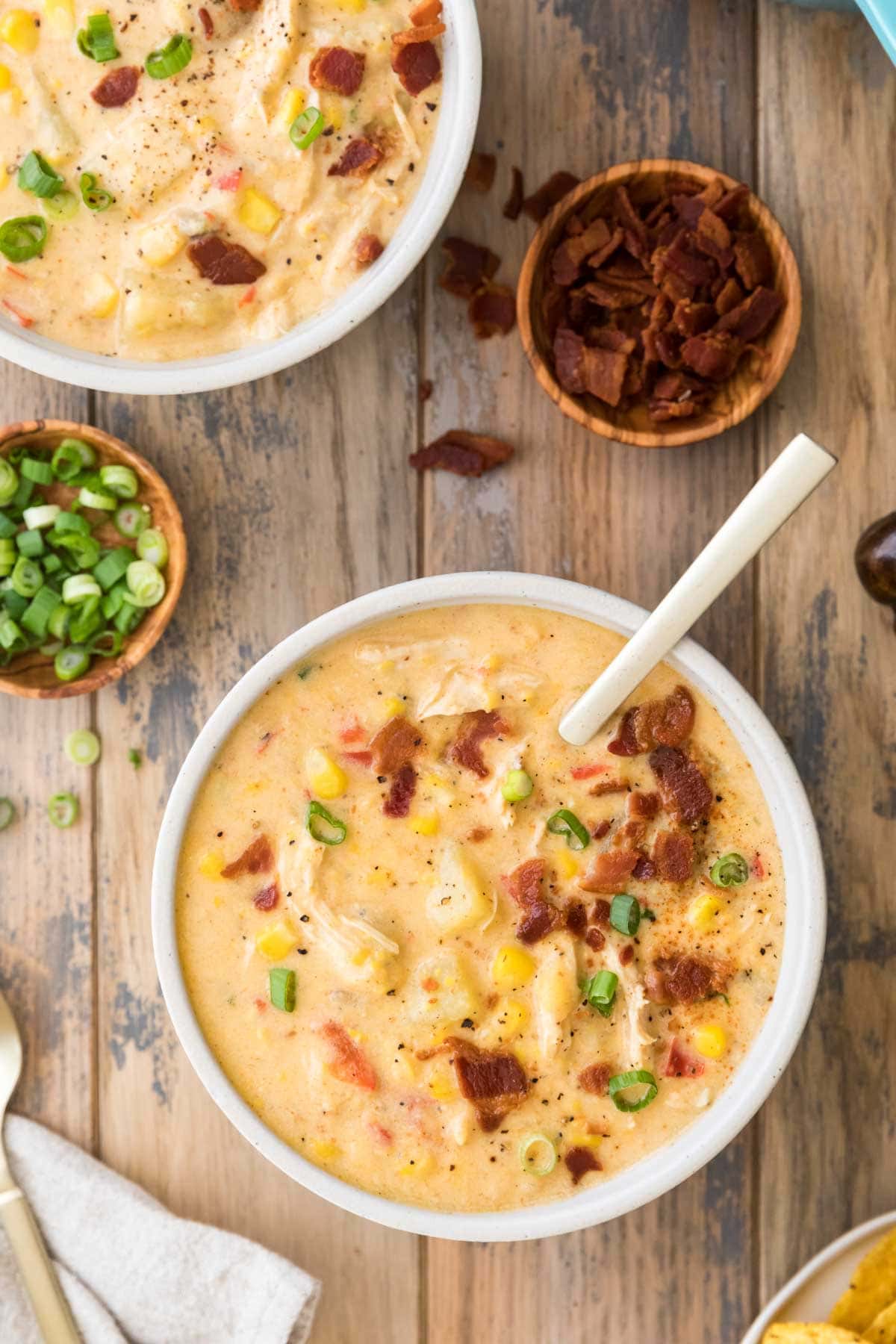 overhead view of two bowls of chowder topped with bacon and scallions
