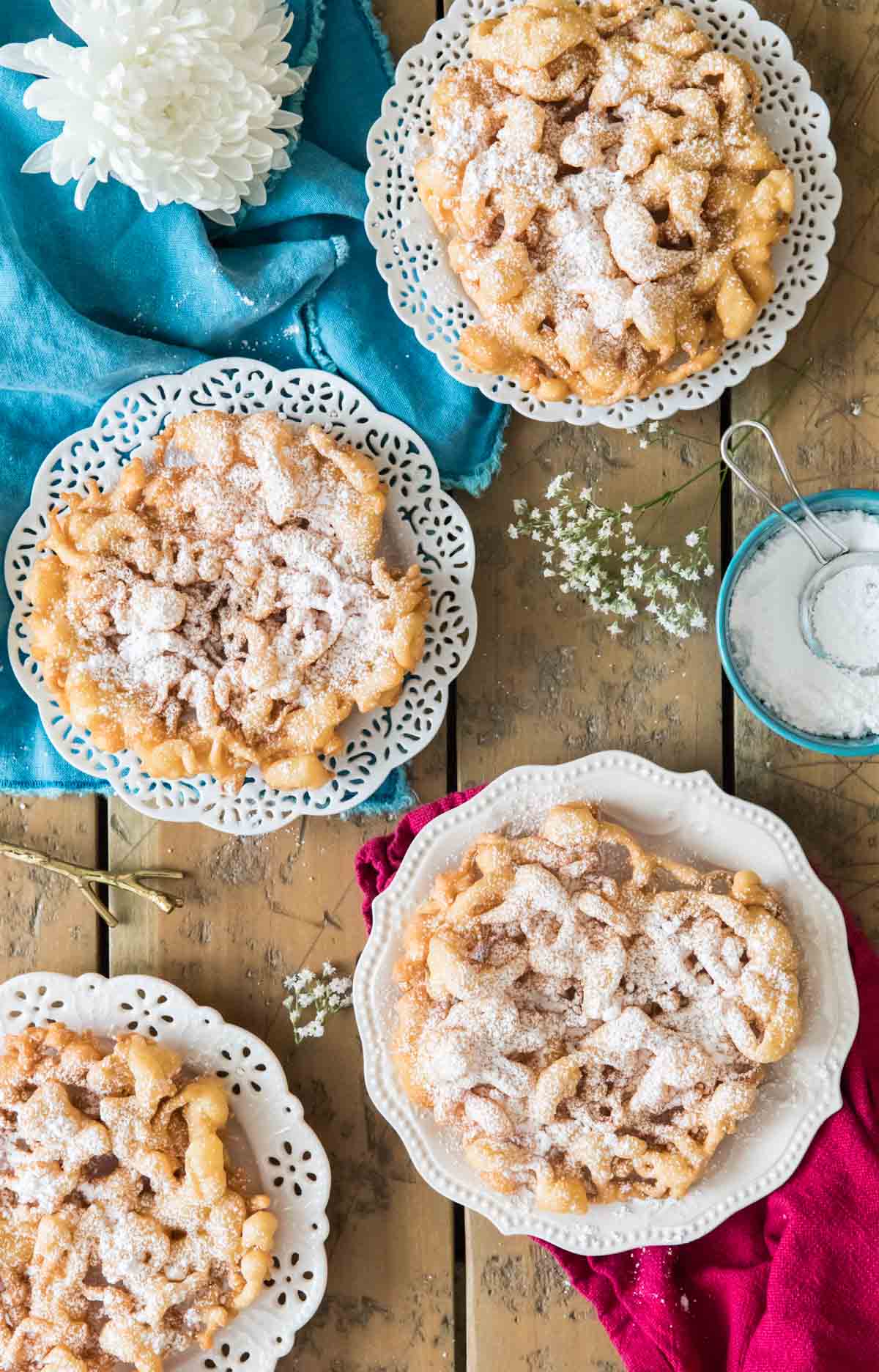 overhead view of homemade funnel cakes on white plates