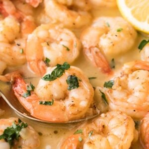 garlic butter shrimp being spooned out of a saucepan