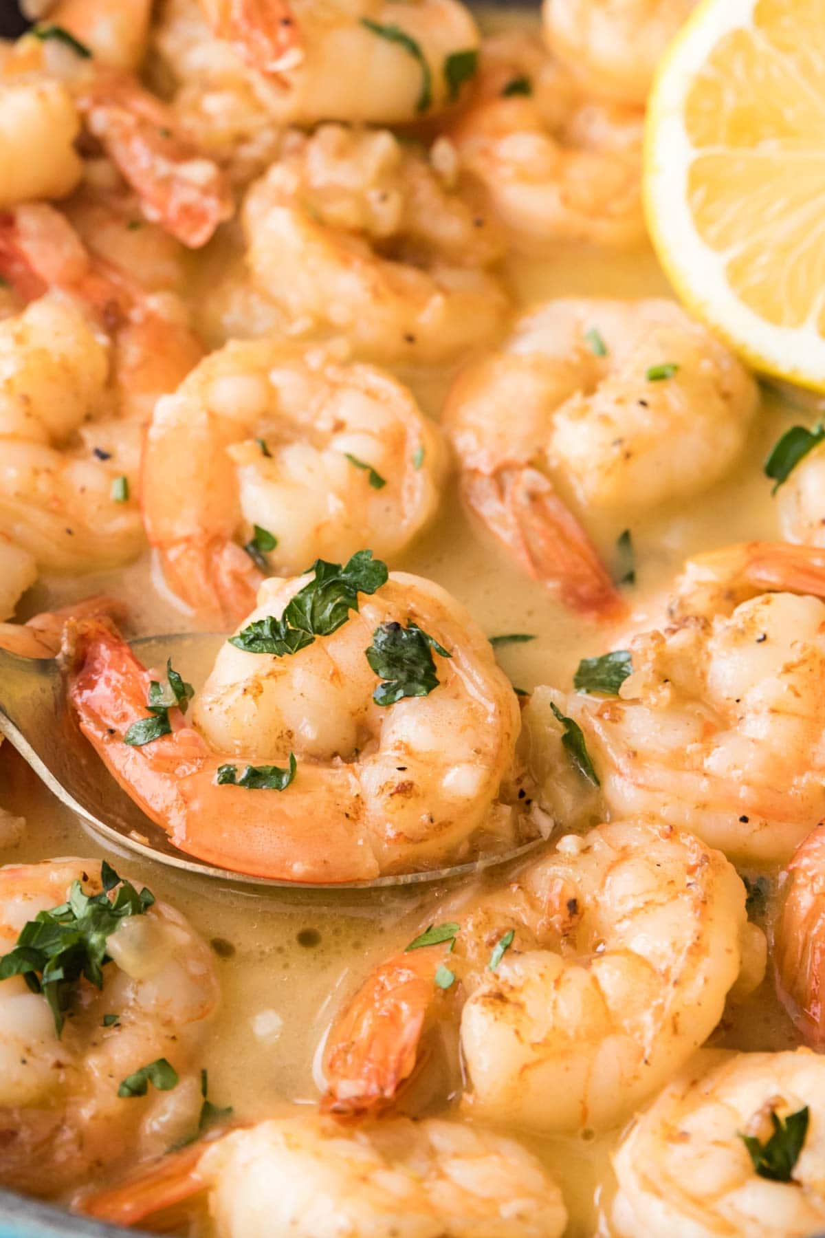 garlic butter shrimp being spooned out of a saucepan