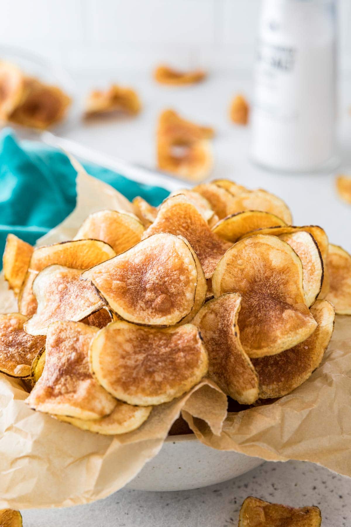 golden brown potato chips in a parchment lined white bowl