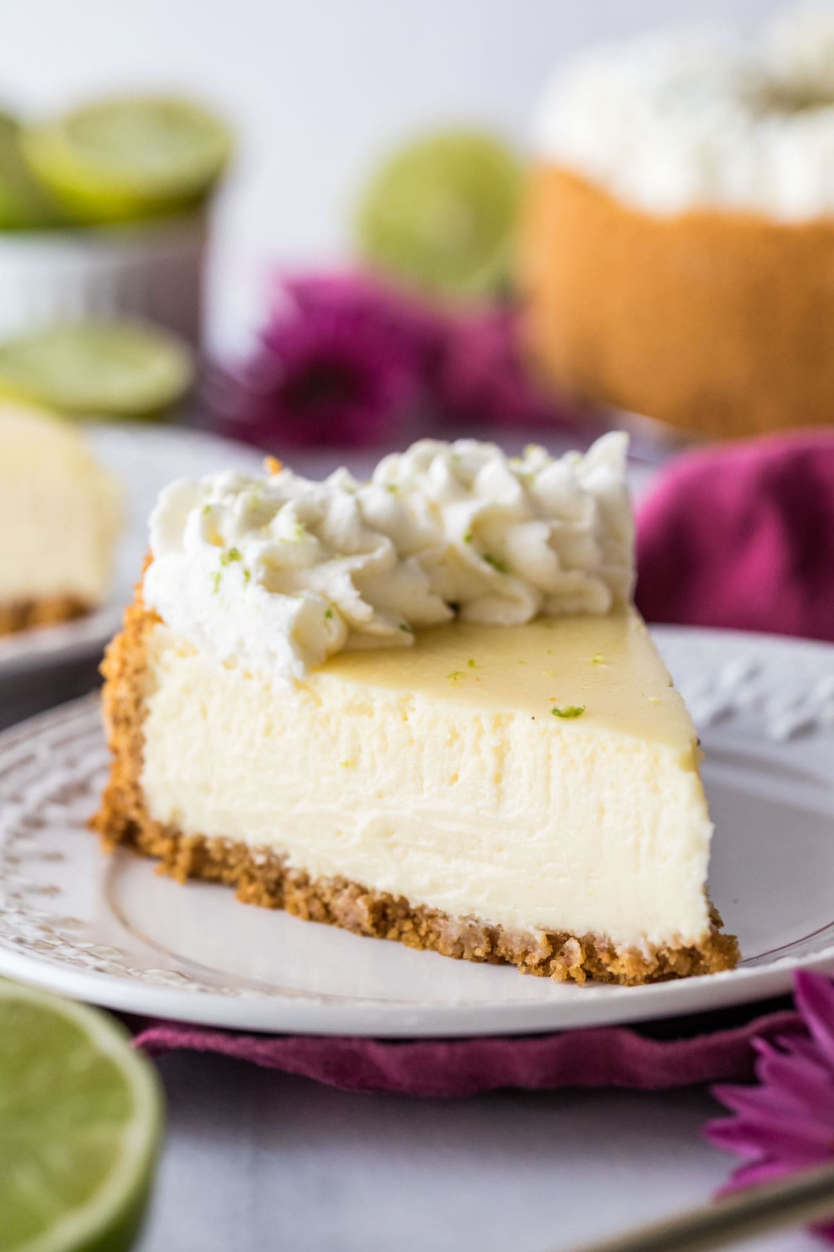 slice of key lime cheesecake topped with swirls of whipped cream and lime zest
