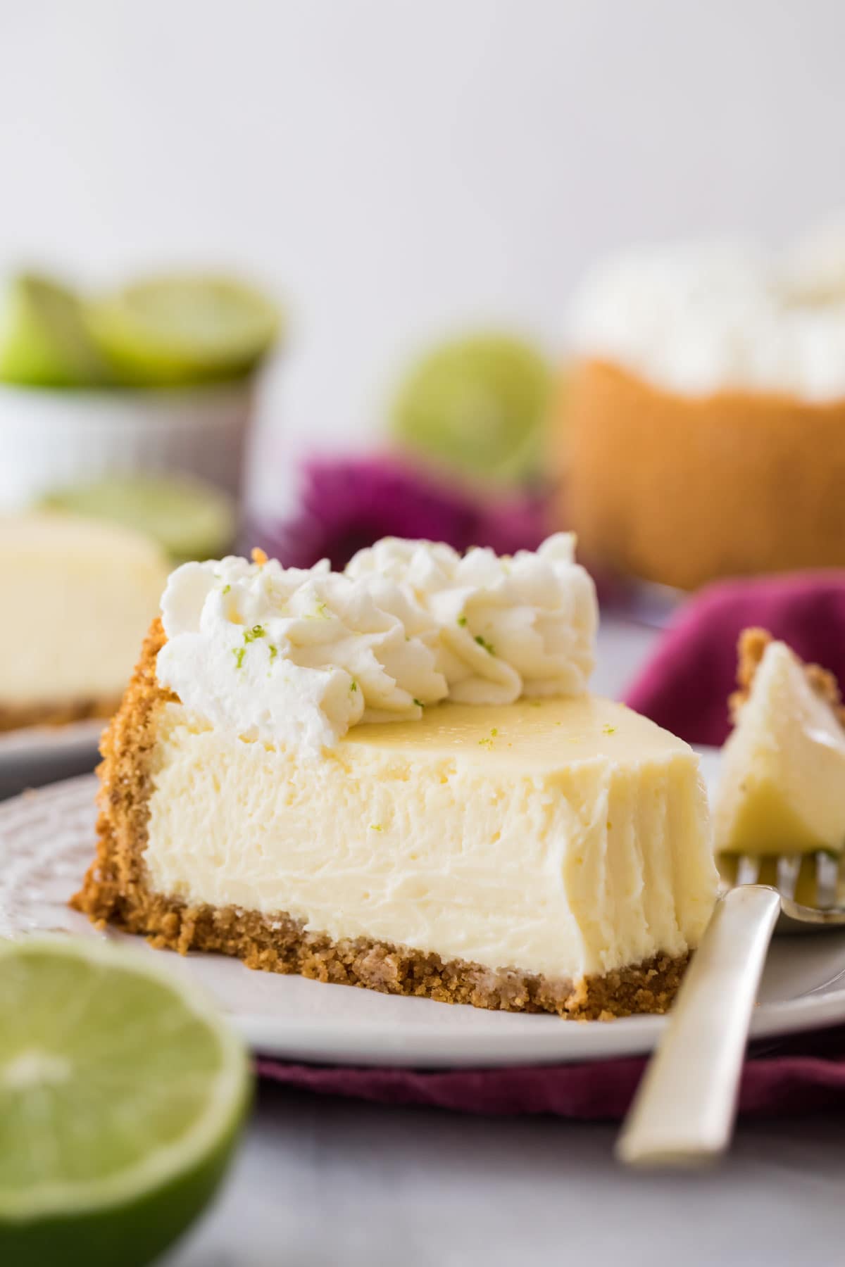 one forkful missing from a slice of cheesecake topped with piped whipped cream and lime zest