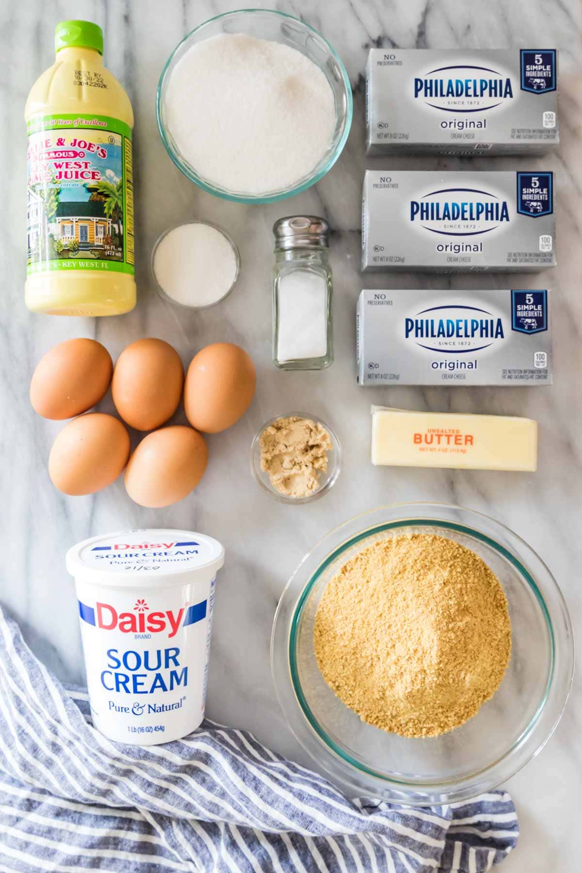 overhead view of ingredients including key lime juice, graham cracker crumbs, eggs, cream cheese, and more