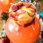 large glass pitcher of homemade strawberry lemonade with sliced strawberries and lemons as a garnish