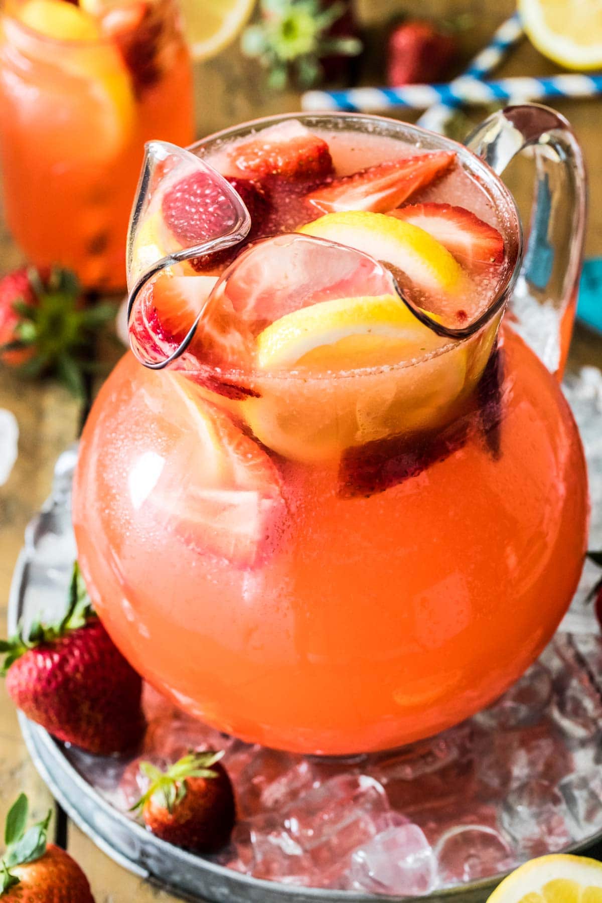 large glass pitcher of homemade strawberry lemonade with sliced strawberries and lemons as a garnish