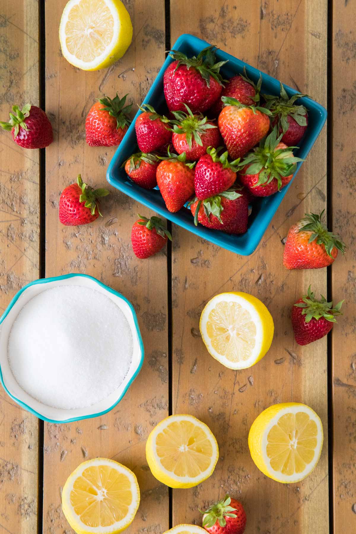overhead view of ingredients including strawberries, lemons, and sugar