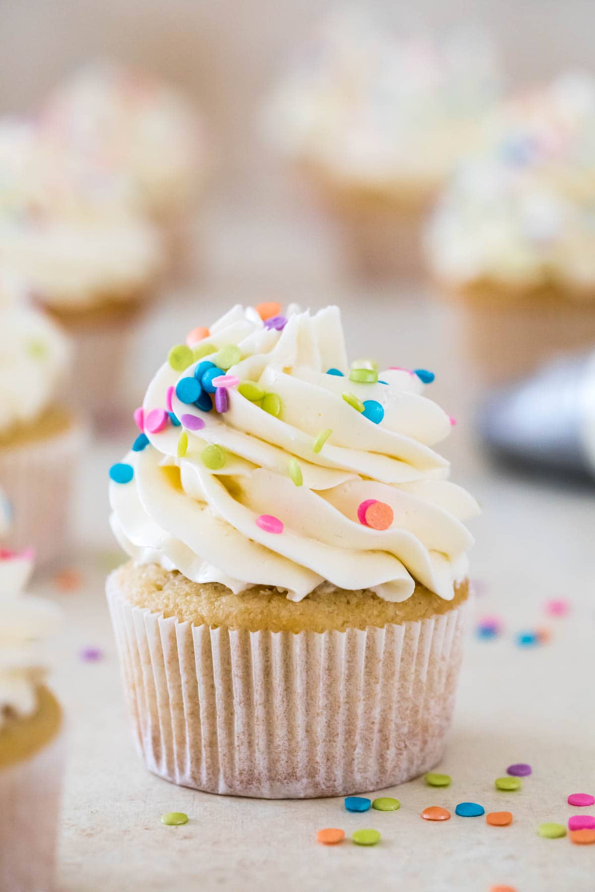 vanilla cupcake topped with piped swiss meringue buttercream and rainbow sprinkles