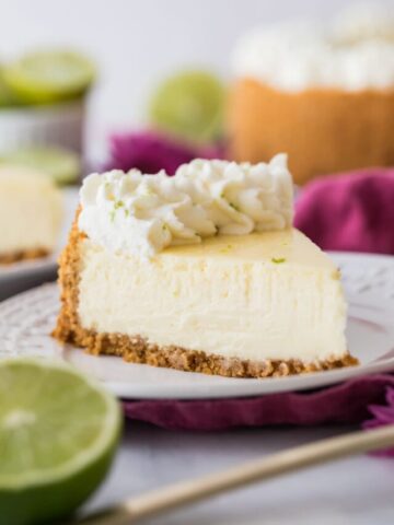 slice of cheesecake topped with piped whipped cream and lime zest