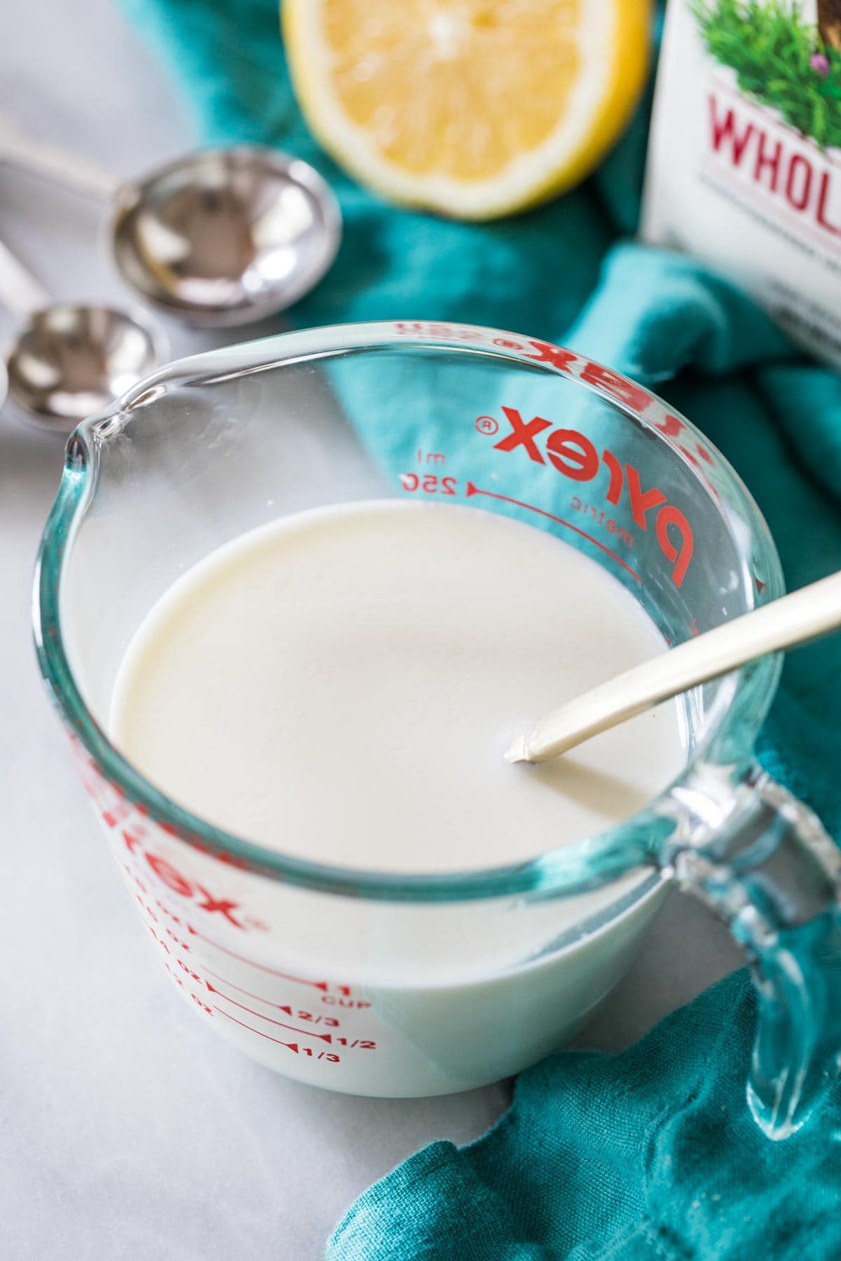 spoon resting in a liquid measuring cup of homemade buttermilk