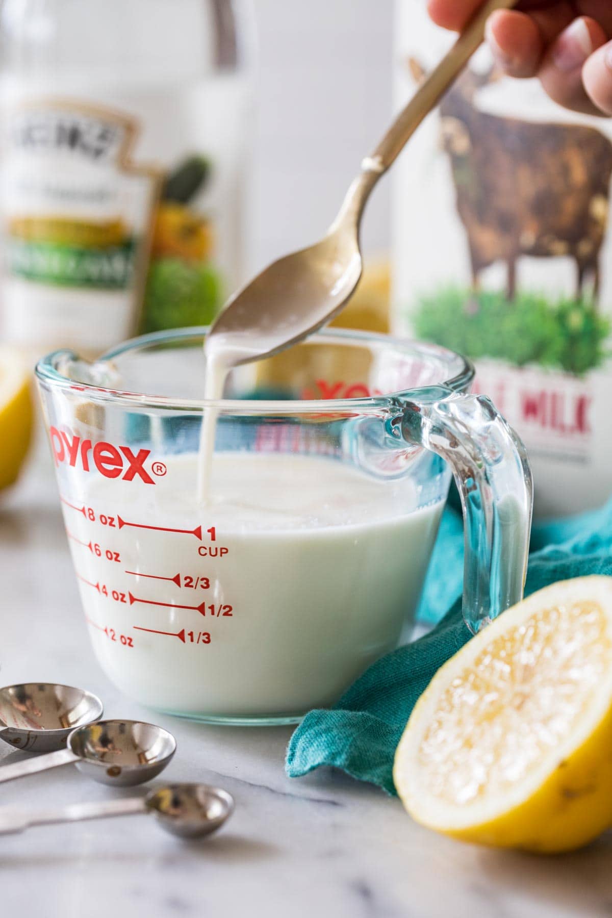 spoon stirring acid into milk to make homemade buttermilk