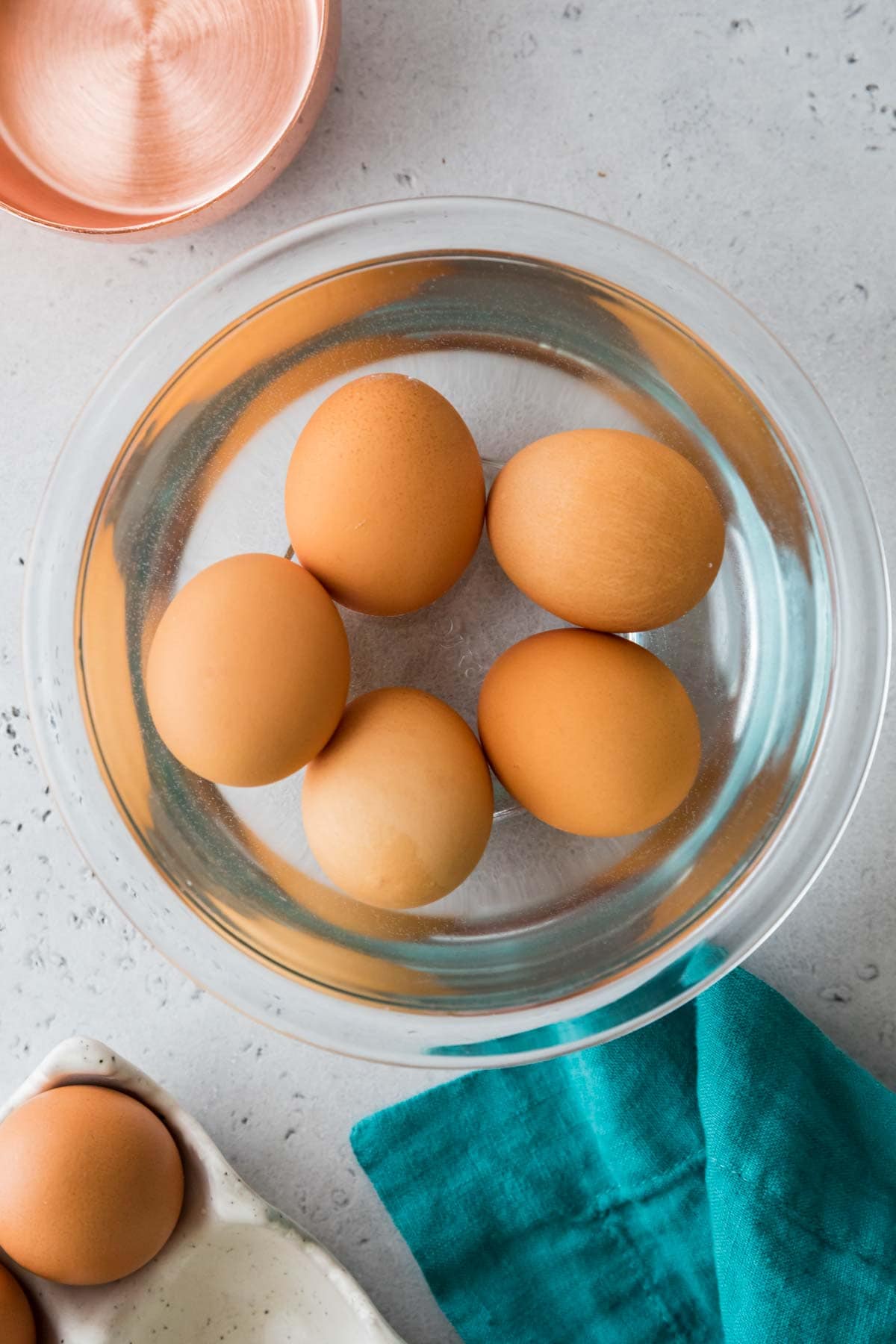 overhead view of five brown eggs in a bowl of warm water