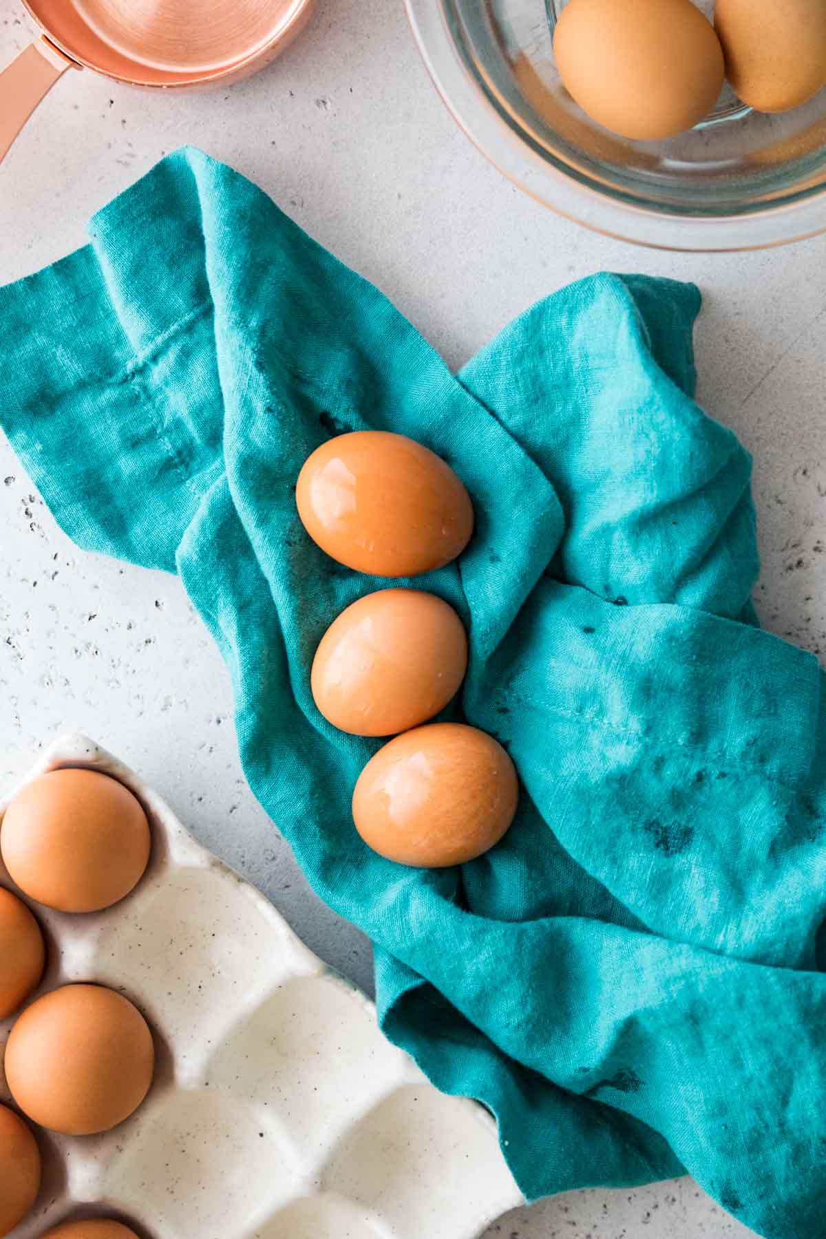 overhead view of three brown eggs being dried on a teal towel