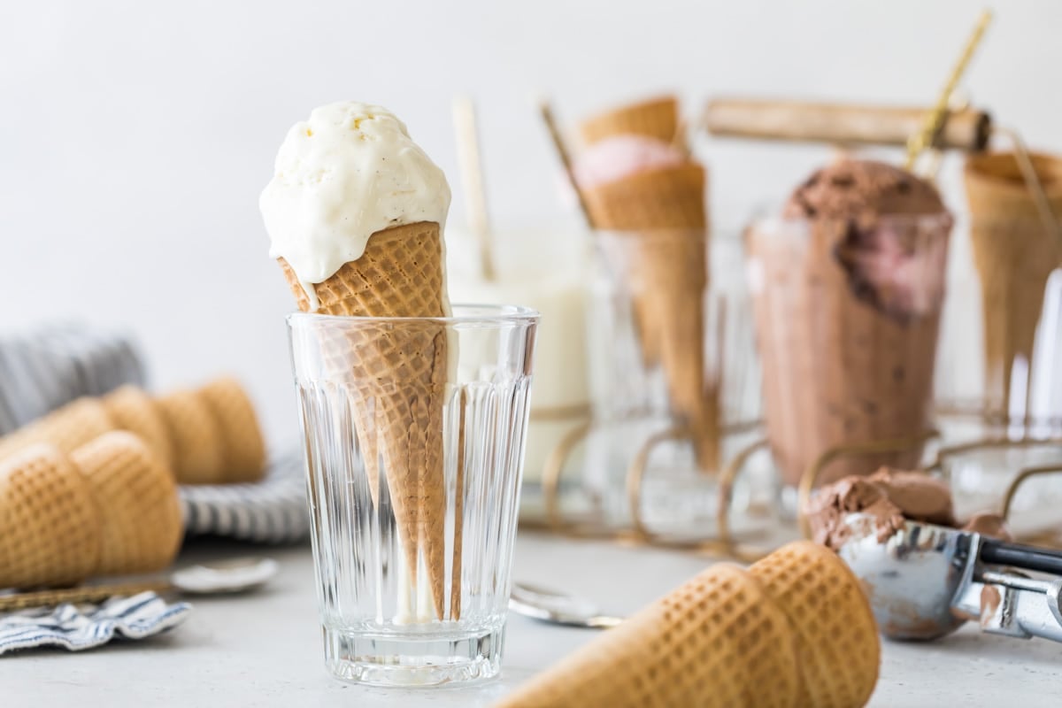 vanilla ice cream cone standing in a clear drinking glass surrounded by ice cream cones