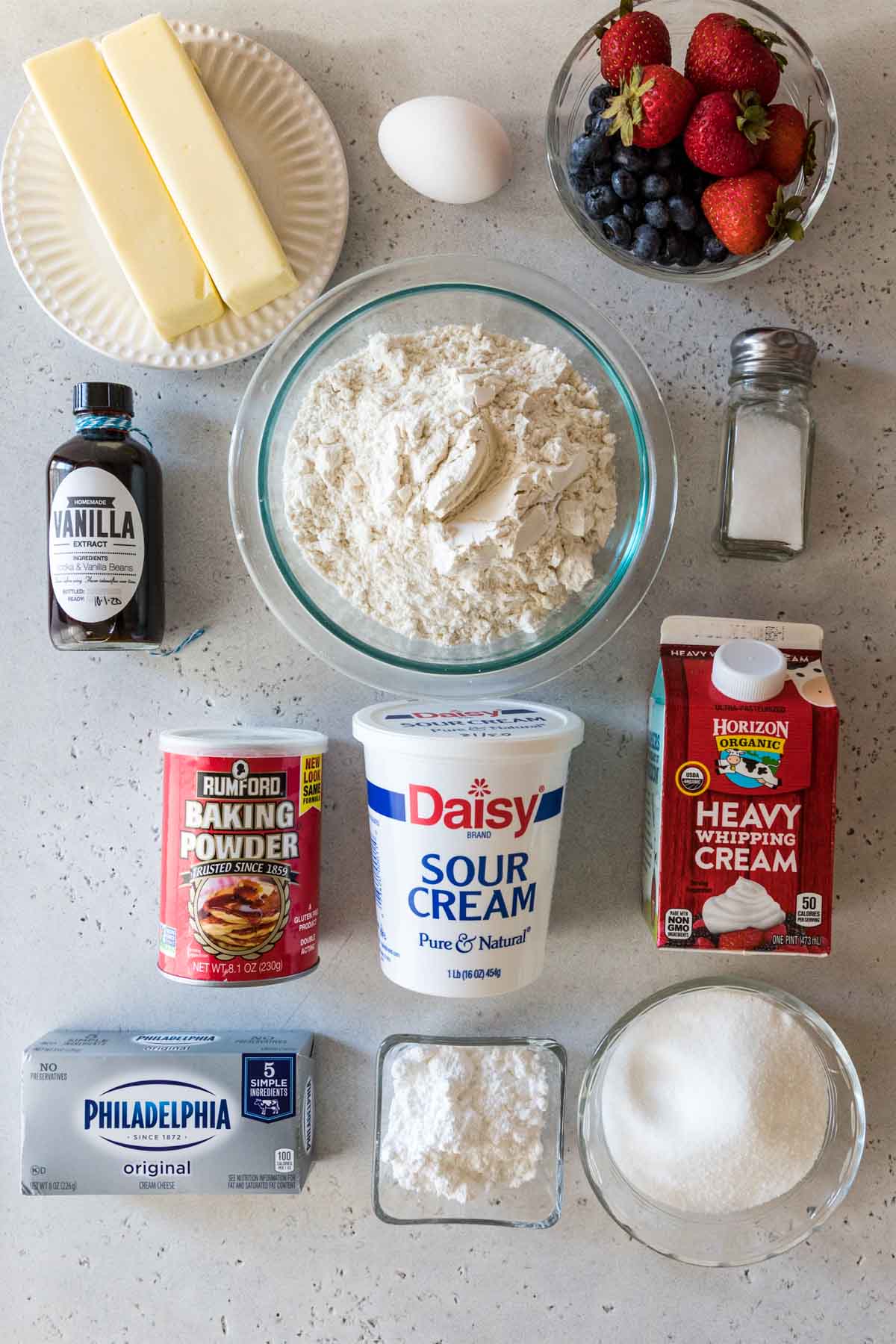 overhead view of ingredients including butter, sour cream, berries, heavy cream, cream cheese, and more