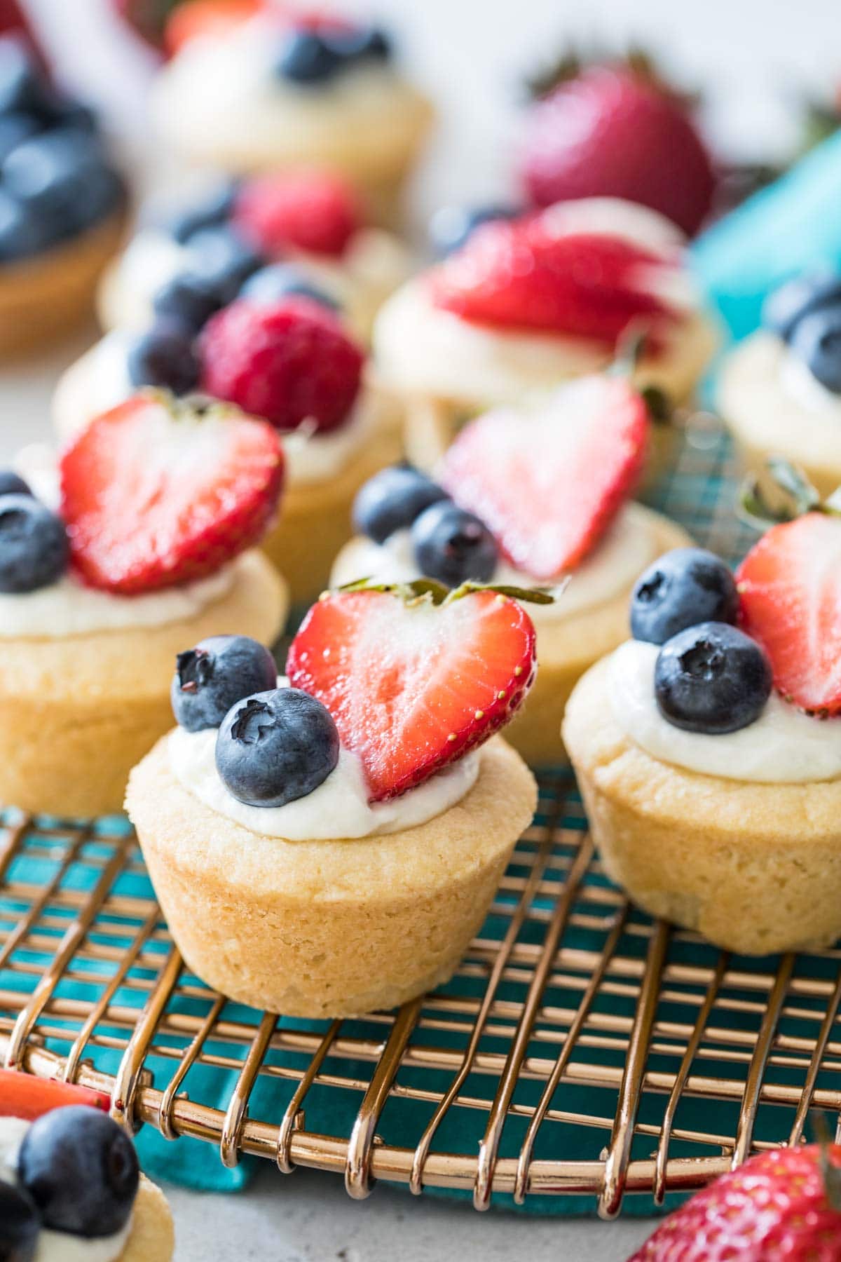 cheesecake bites in a sugar cookie crust topped with blueberries and sliced strawberries