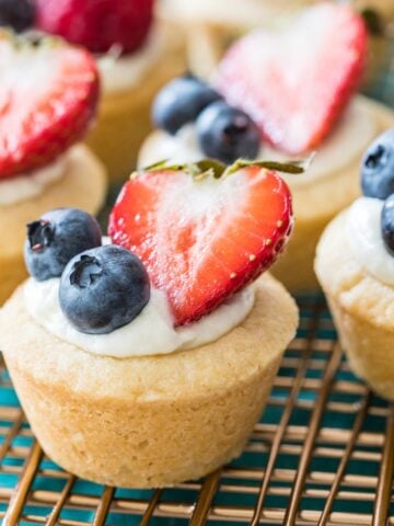 cheesecake bites in a sugar cookie crust topped with blueberries and sliced strawberries