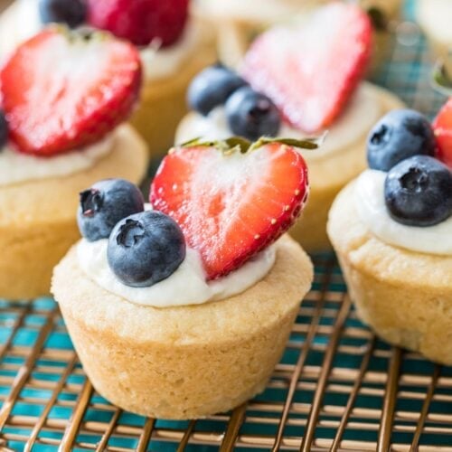 cheesecake bites in a sugar cookie crust topped with blueberries and sliced strawberries