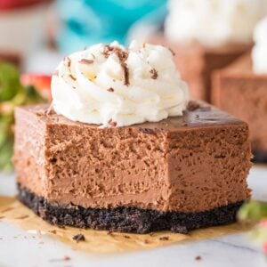 square cut chocolate cheesecake bar topped with whipped cream missing one bite