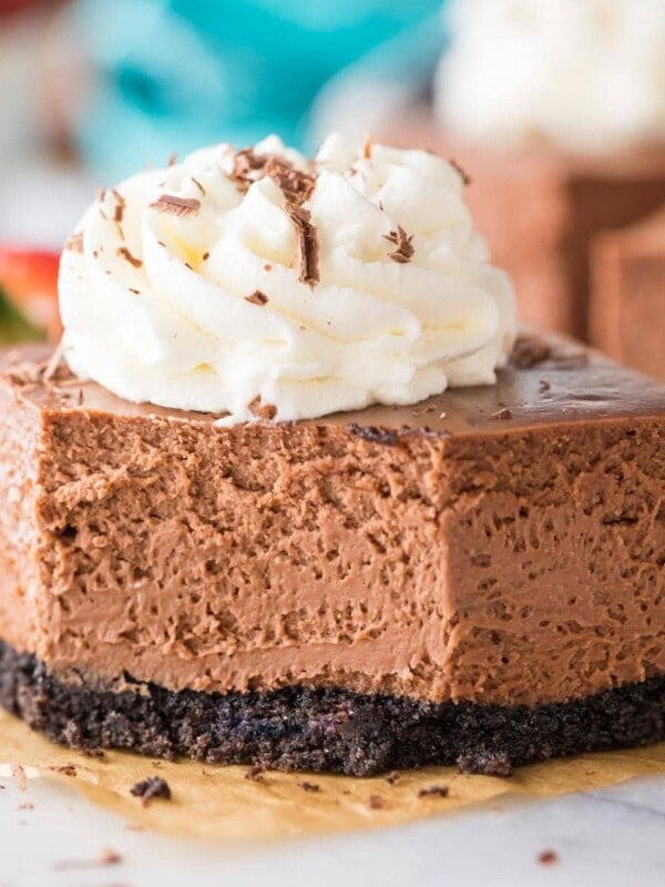 square cut chocolate cheesecake bar topped with whipped cream missing one bite