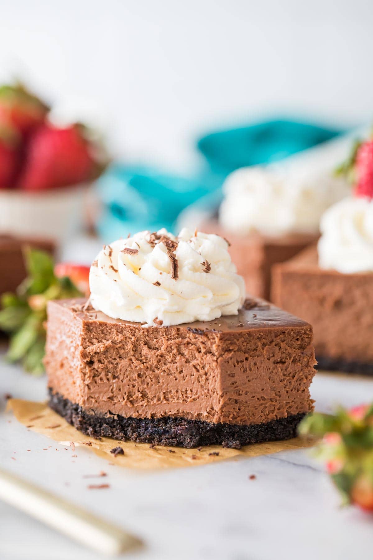 square cut chocolate cheesecake bar topped with whipped cream missing one bite