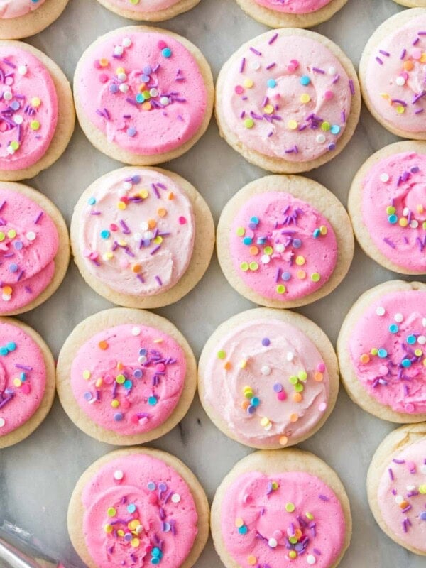 overhead view of homemade lofthouse cookies topped with varying shades of pink icing and sprinkles