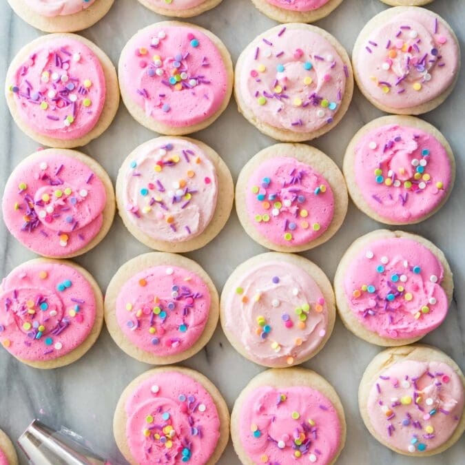 overhead view of homemade lofthouse cookies topped with varying shades of pink icing and sprinkles