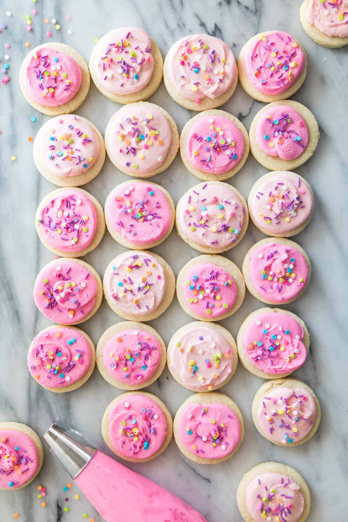 overhead view of homemade lofthouse cookies topped with varying shades of pink icing and sprinkles