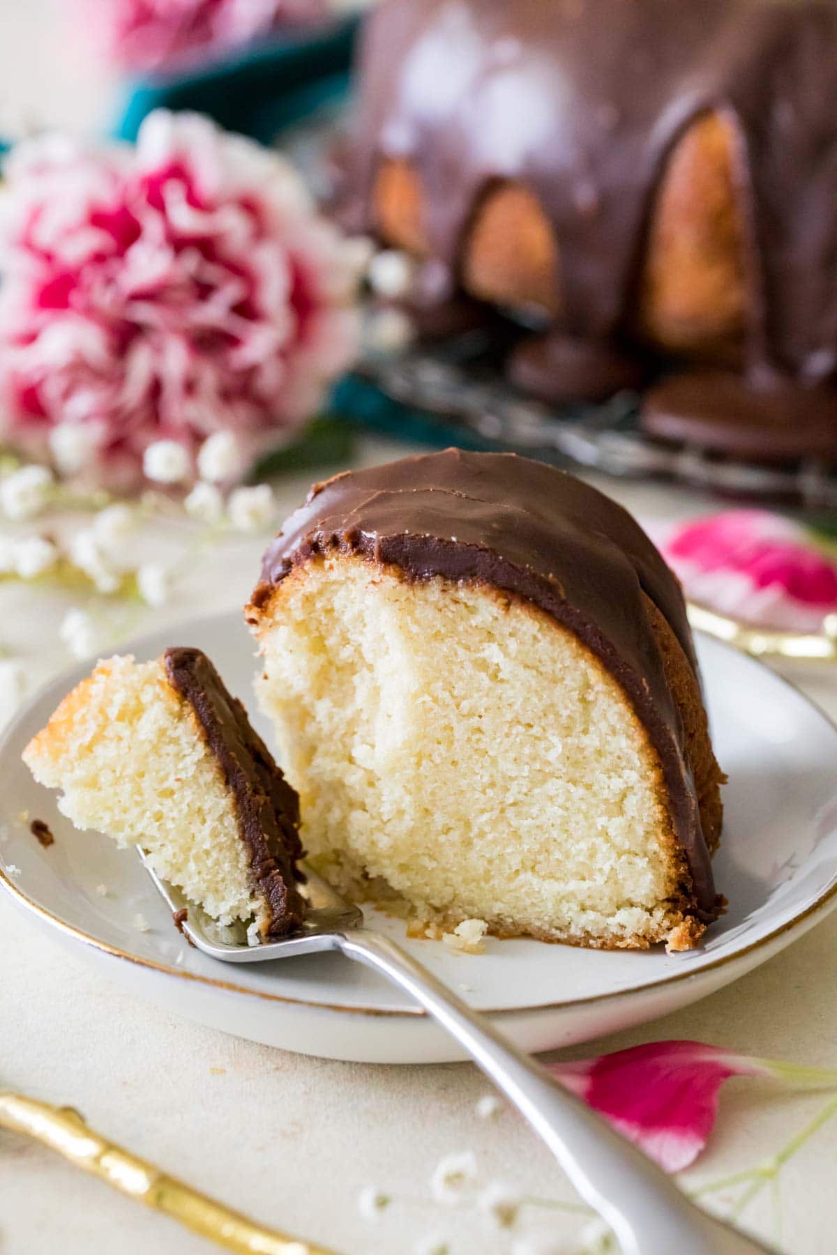 fork scooping a bite from a slice of bundt cake topped with fudgy chocolate frosting