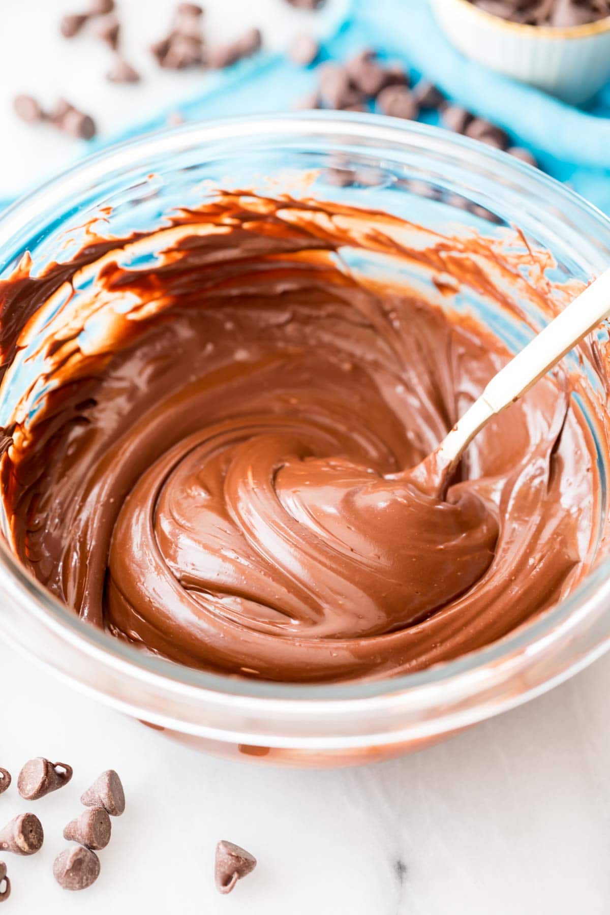 melted chocolate in a clear bowl being stirred by a spoon