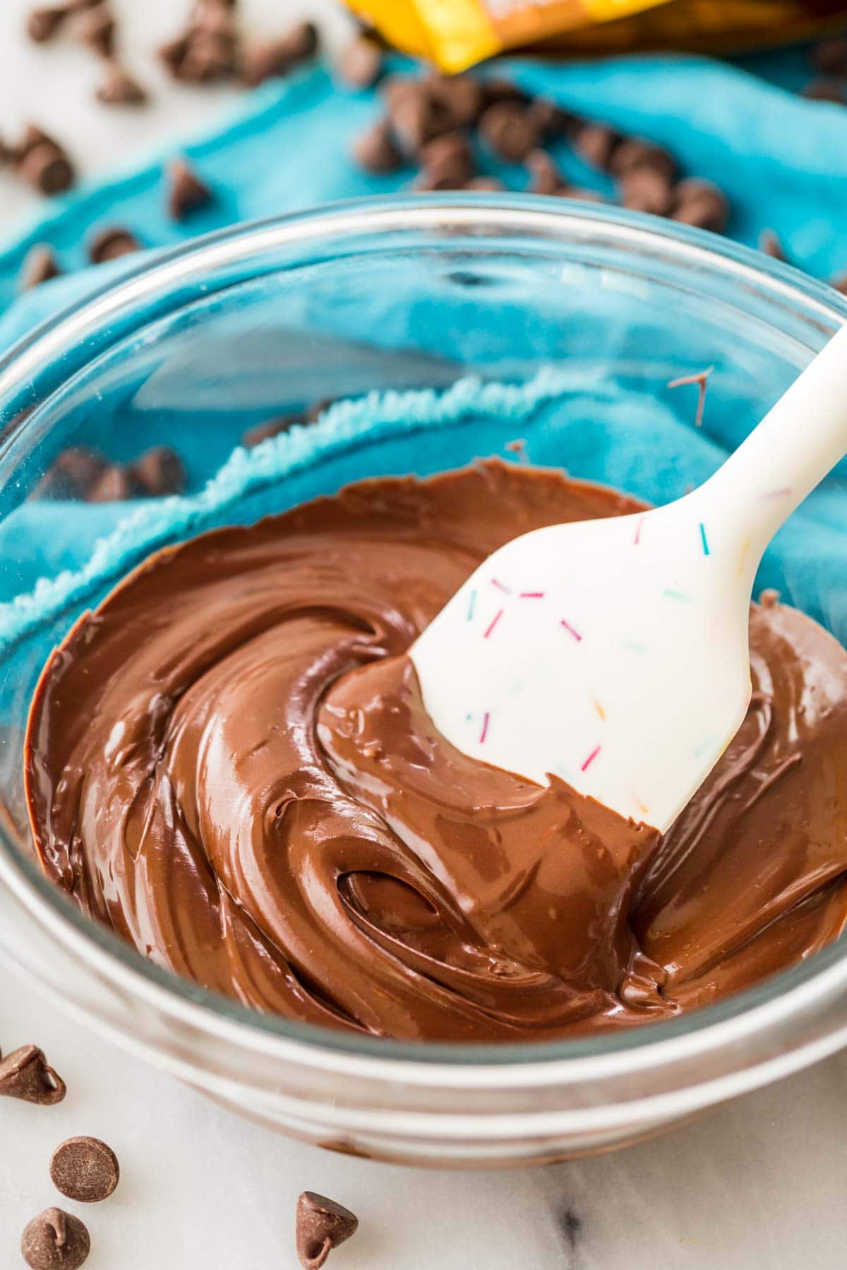 spatula stirring melted chocolate in a clear bowl