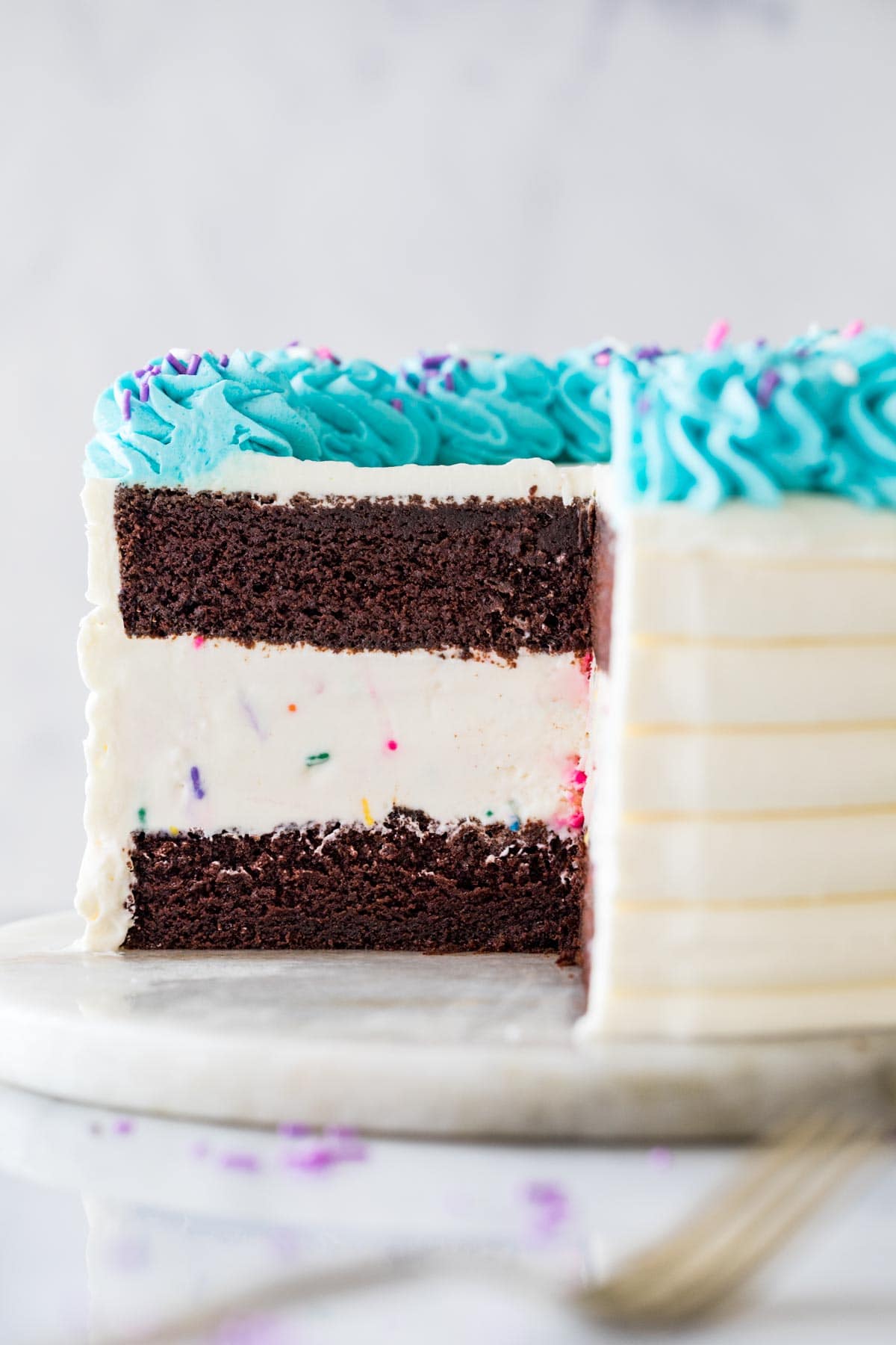 close-up view of the interior of an ice cream cake made with chocolate cake, vanilla ice cream, and turquoise whipped cream frosting