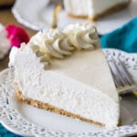 slice of no-bake cheesecake topped with whipped cream on a white decorative plate