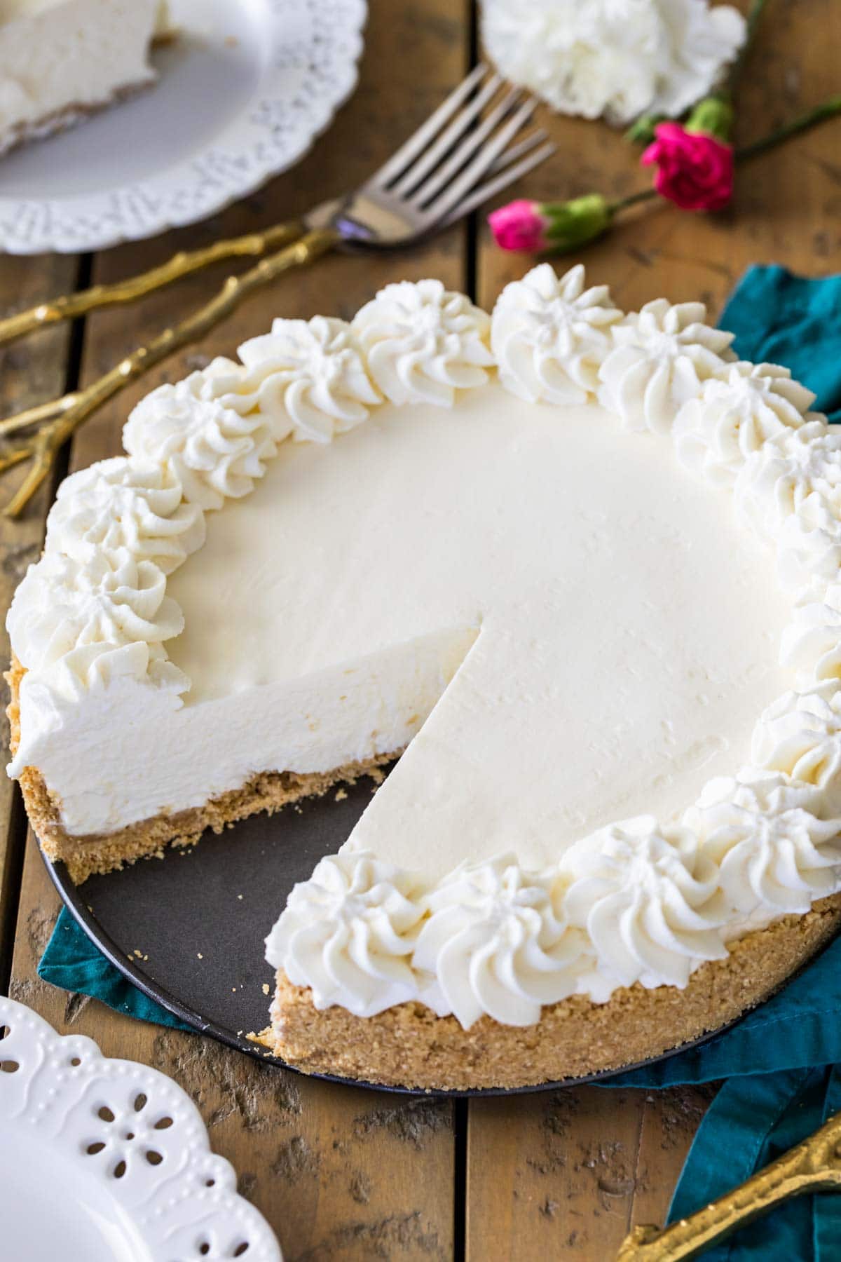 whole no-bake cheesecake topped with whipped cream missing one slice