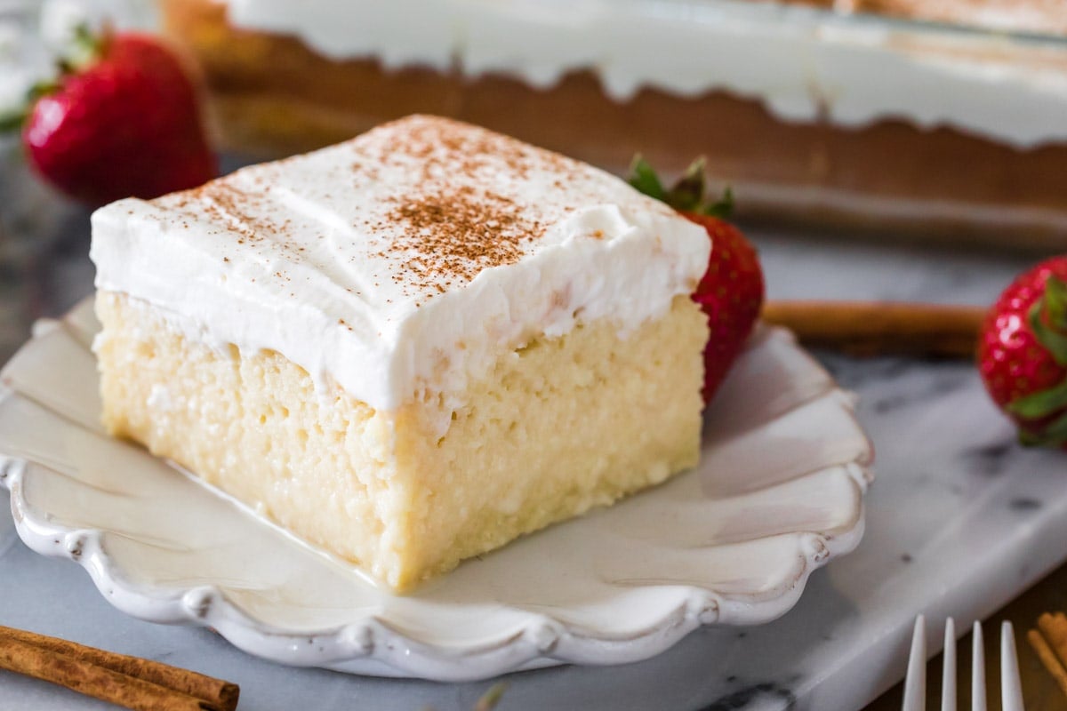 square slice of cake that's been soaked with a milk mixture and topped with whipped cream and cinnamon