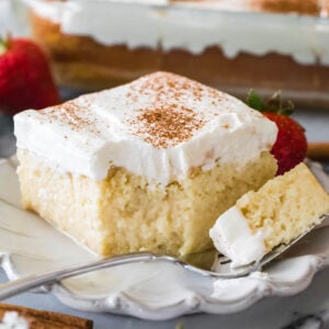 square slice of tres leches cake with one forkful sitting on the plate beside it