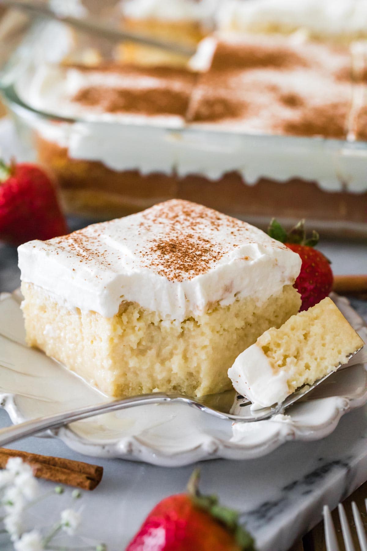 square slice of tres leches cake with one forkful sitting on the plate beside it