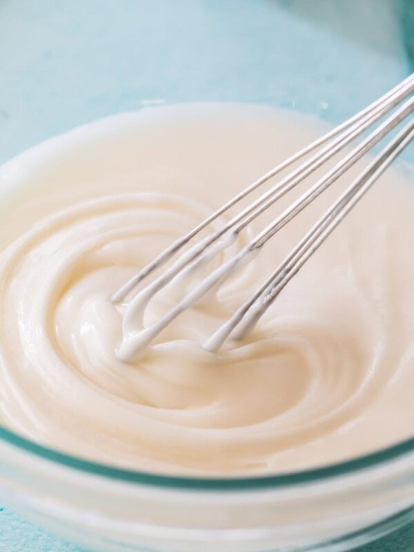 whisk stirring vanilla glaze in a clear glass bowl