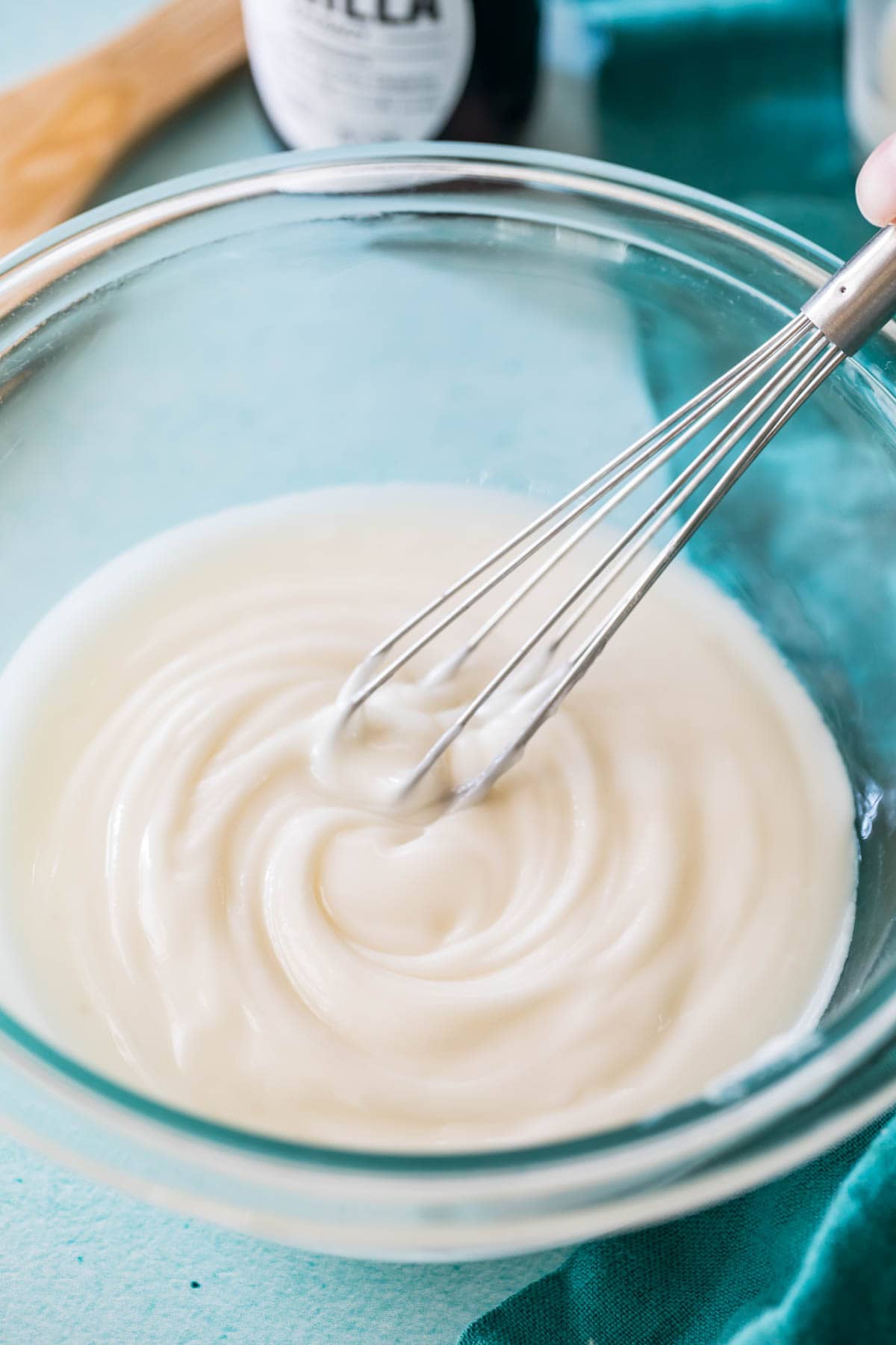 whisk stirring a glaze in a glass bowl