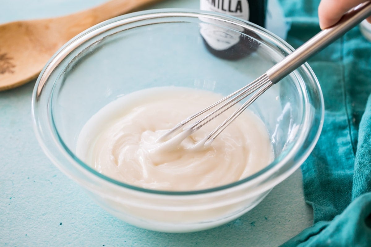 whisk stirring a glaze in a glass bowl