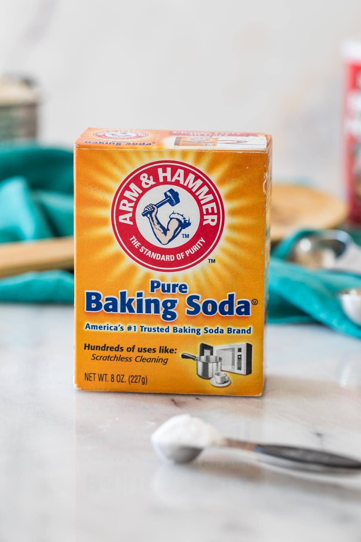 box of baking soda with a measuring spoon in front of it