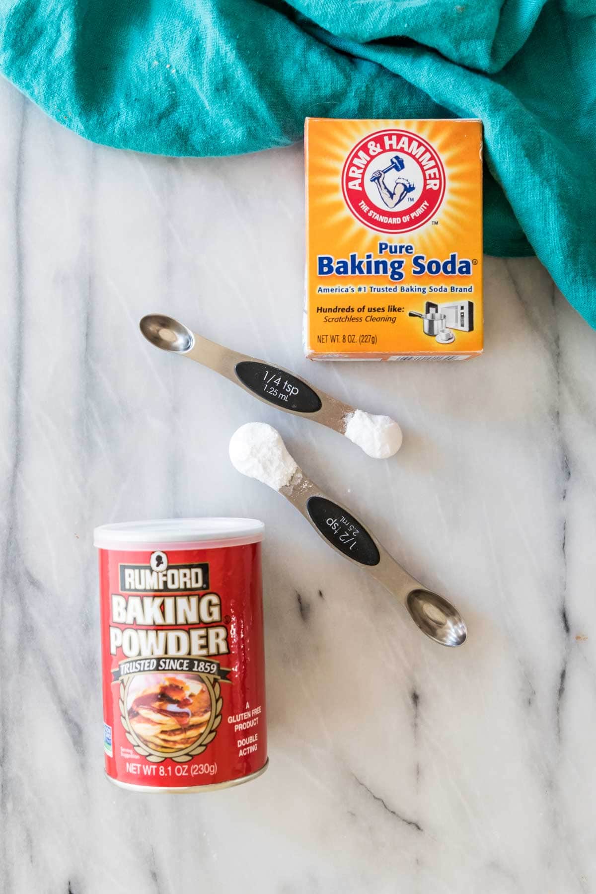 overhead view of baking powder and baking soda containers with measuring spoons between them